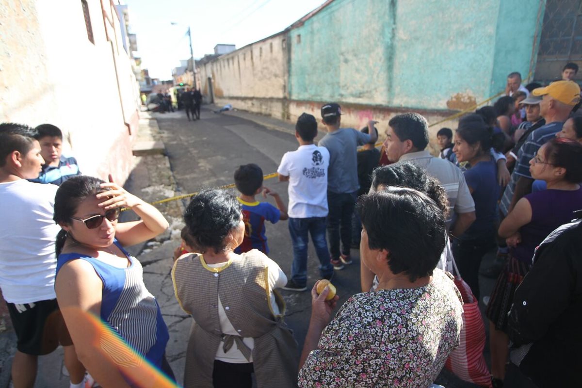 Vecinos del barrio Gerona, en zona 1, observan el cadáver de la víctima del ataque a balazos. (Foto Prensa Libre: Óscar Rivas)