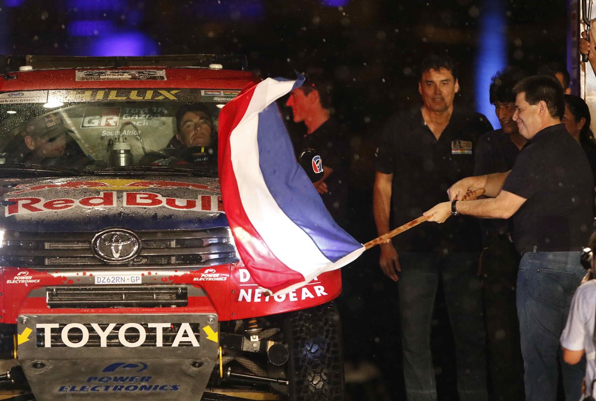 El presidente paraguayo, Horacio Cartes da el banderazo de salida al piloto sudafricano Giniel De Villiers, durante la largada del Rally Dakar 2017 en la ciudad de Asunción. (Foto Prensa Libre: EFE).