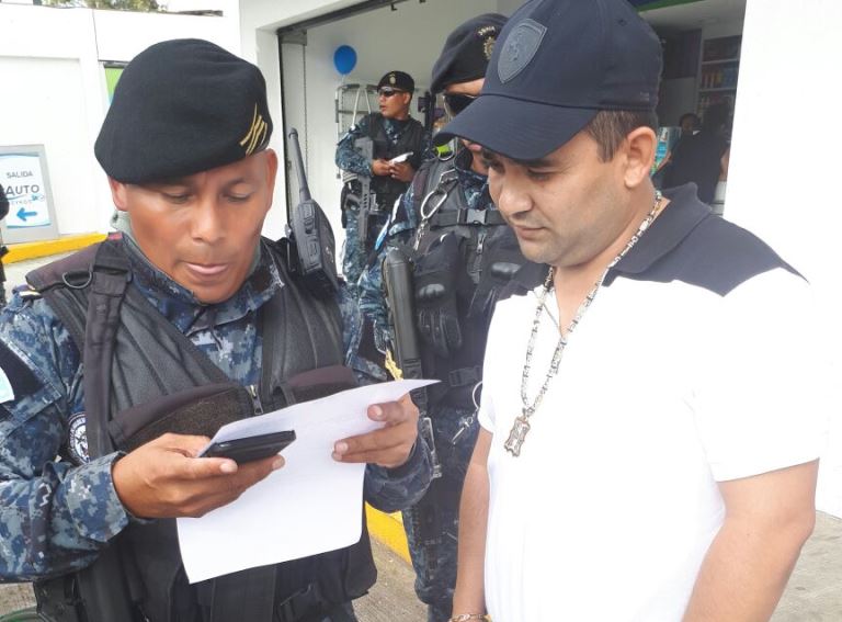 Agente antinarcóticos verifica la identidad del supuesto narco, Hugo Alejandro Chacón Cerna, el motivo de su detención. (Foto PNC)