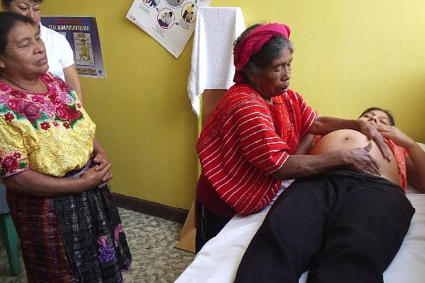 Una comadrona examina a  mujer embarazada, en Sololá.