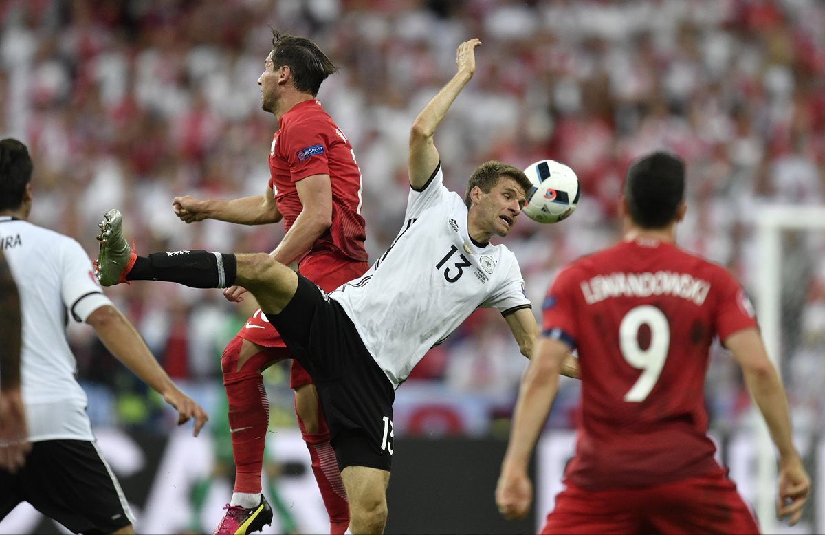 Thomas Mueller pelea la pelota con el polaco Grzegorz Krychowiak en una acción del juego de hoy. (Foto Prensa Libre: AP)