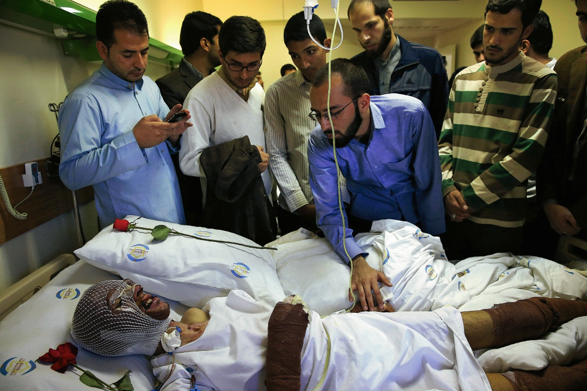 Un hombre que resultó herida por lo sbombardeos en Yemen es visitada por compañeros en un hospital. (Foto Prensa Libre: AP).