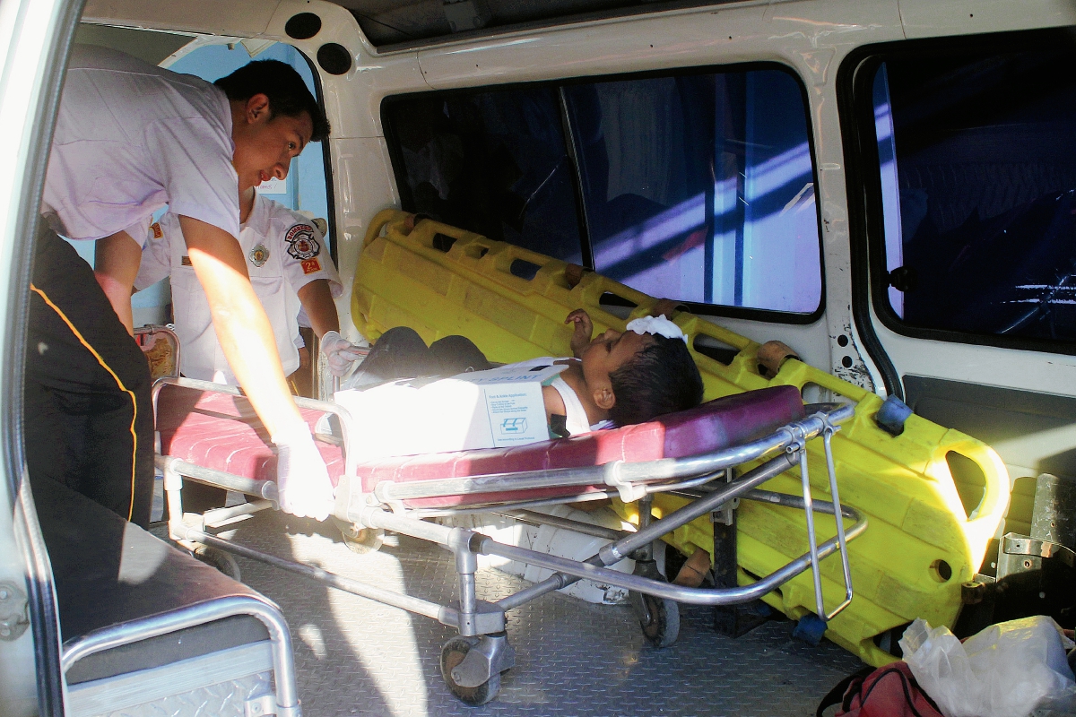 Un socorrista  examina  al niño que cayó desde la ventana de un autobús en Jalapa, cuando regresaba de una actividad política en la capital. (Foto Prensa Libre: Hugo Oliva)