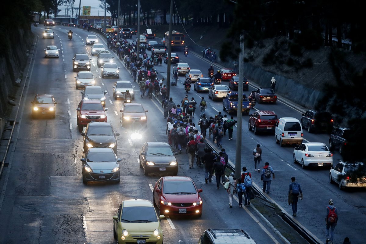 Migrantes hondureños caminan entre el tráfico hacia Escuintla, en su travesía hacia Estados Unidos. (Foto Prensa Libre: EFE)