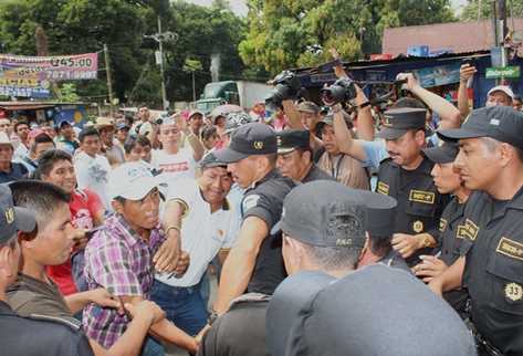 Líderes campesinos buscan proteger a uno de sus compañeros que es agredido por un agente de la PNC. (Foto Prensa Libre: Felipe Guzmán)