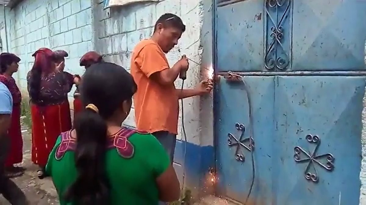 Herrero coloca una estructura de metal para poner un candado en la puerta de la escuela de Tijom, Nebaj, Quiché. (Foto Prensa Libre: Héctor Cordero).