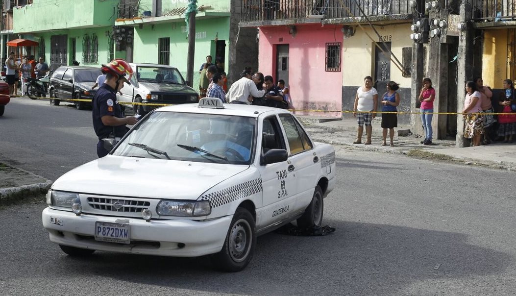 Un socorrista observa el cadáver del taxista ultimado en la colonia 15 de agosto. (Foto Prensa Libre: Paulo Raquec)
