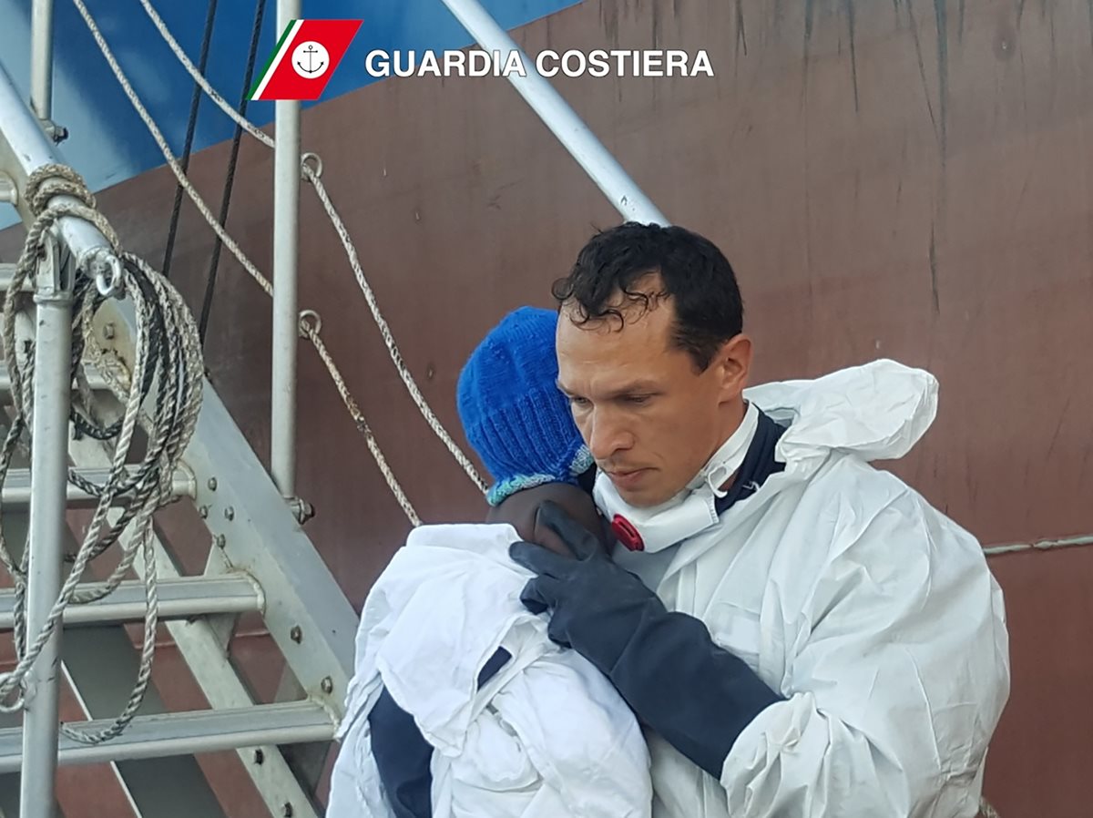 La pequeña Favur es sostenida en brazos por el médico de Lampedusa, Pietro Bartolo. (Foto Prensa Libre: AFP).
