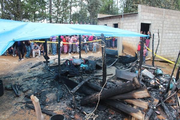 Vecinos observan los restos de la vivienda donde murieron carbonizados los dos niños.