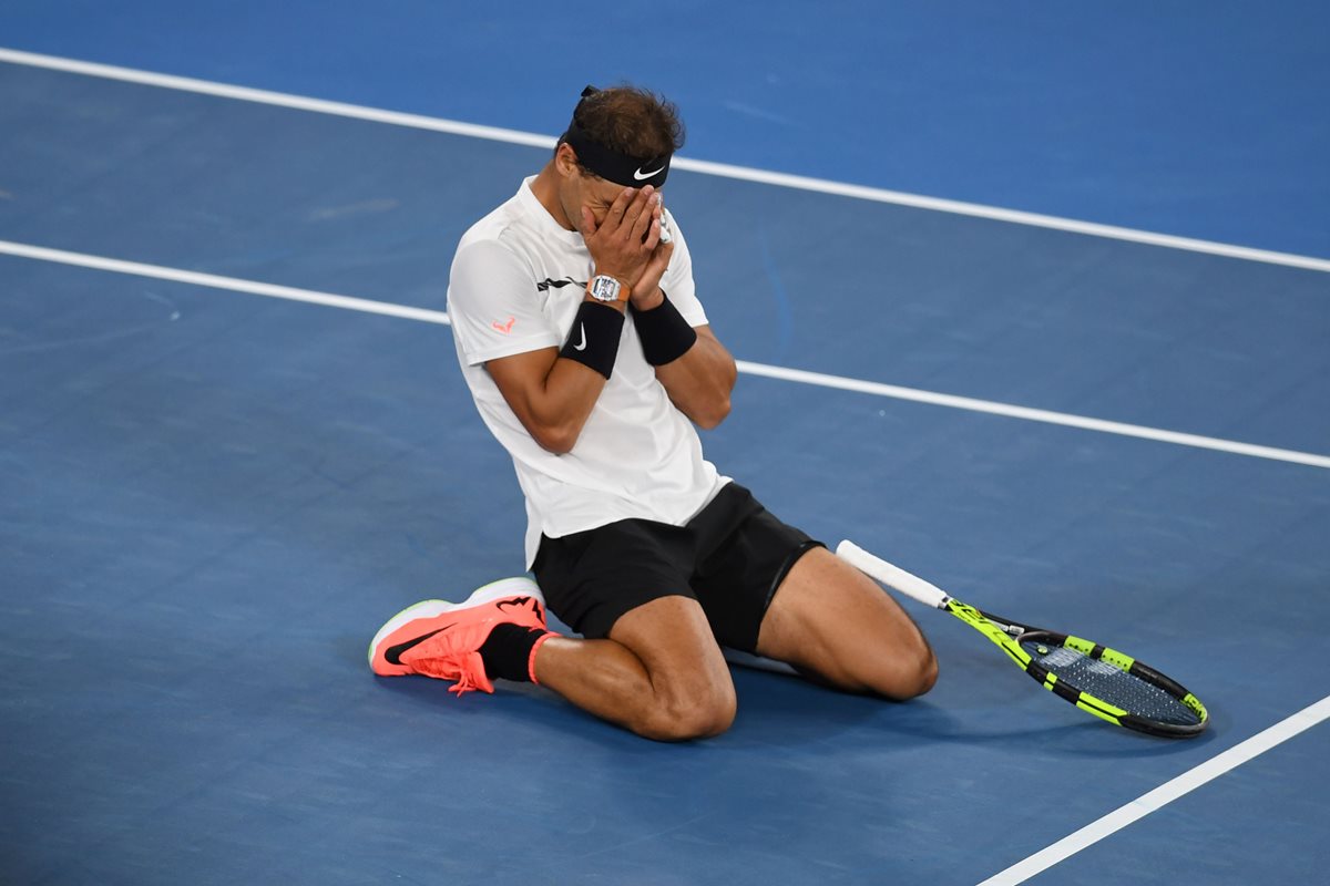 El tenista español Rafael Nadal se arrodilla y celebra la victoria contra Milos Raonic para avanzar a la semifinal del abierto de Australia. (Foto Prensa Libre:AFP)