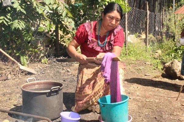Luego de  haber hervido los hilos por 20 minutos, se sumergen de manera repetida en  agua con tinte. (Foto Prensa Libre: Ángel Julajuj)