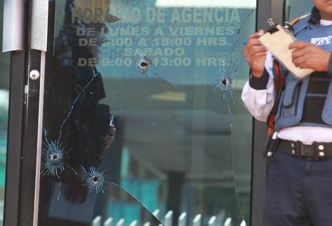 Cuatro perforaciones de bala quedaron en la puerta de la agencia bancaria (Foto Prensa Libre: E. Paredes)