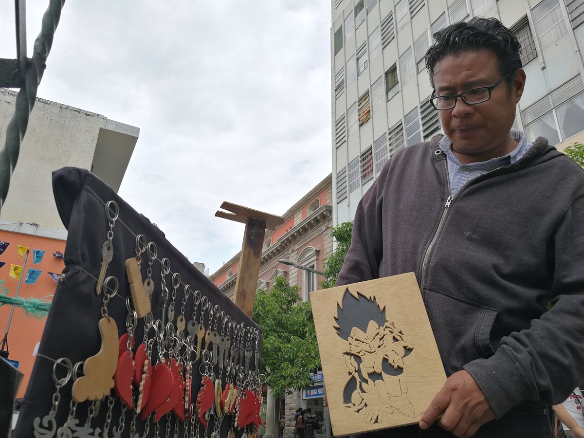 Cristian Santos hace rostros en madera y los vende en la Sexta Avenida de la zona 1 de la capital. (Foto Prensa Libre: César Pérez)
