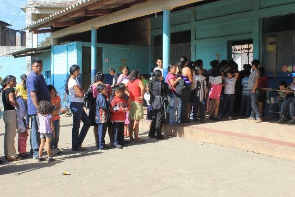 Padres de familia y niños  hacen fila en la escuela José Domingo Guzmán para recibir la ayuda.