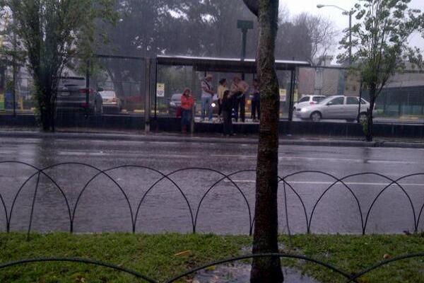 Usuarios de bus se suben a las bancas para evitar que los carros los empapen. (Foto Prensa Libre: Irving Escobar)