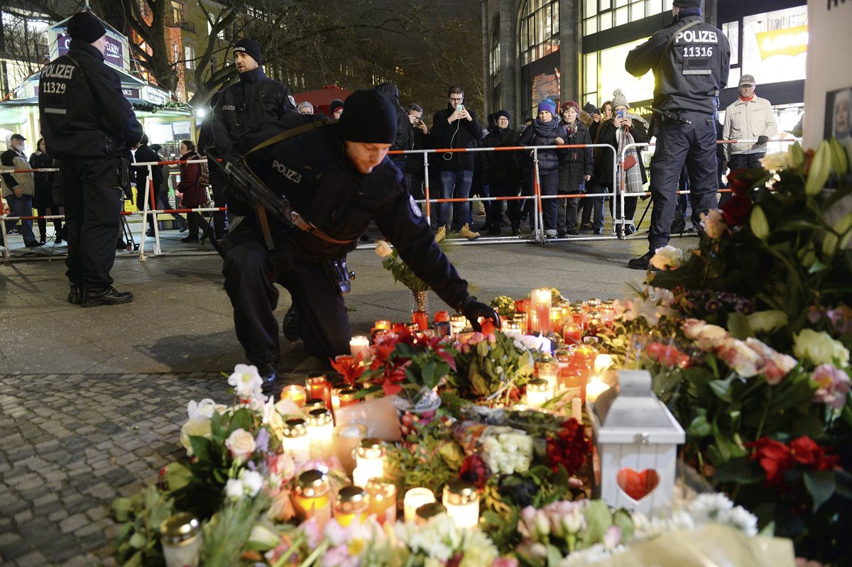 Un policía coloca flores y velas en memoria de las víctimas del atentado en Berlín. (Foto Prensa Libre: EFE).