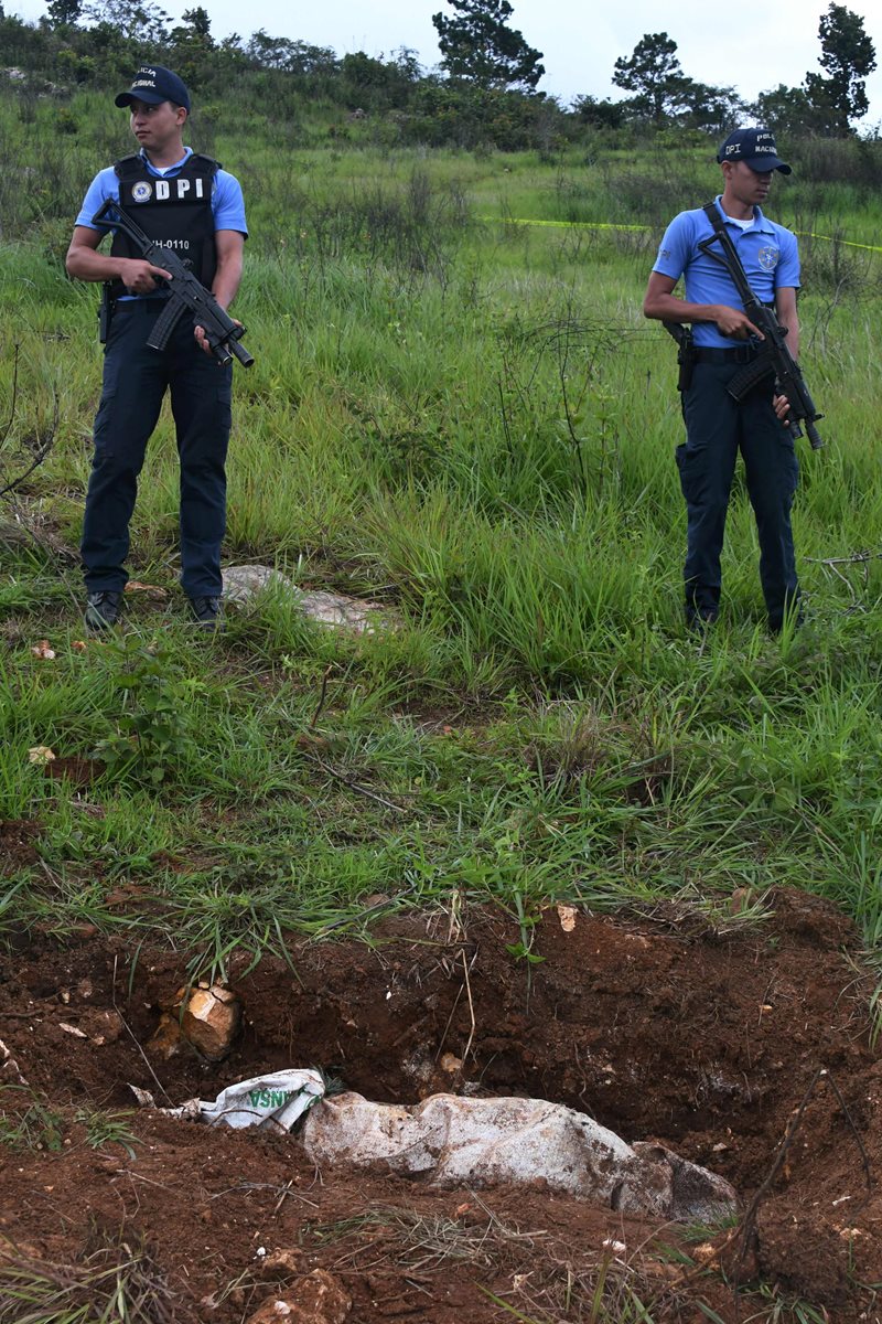 Efectivos de la policía vigilan la fosa común utilizada por pandilleros para enterrar a las víctimas secuestradas.(AFP).