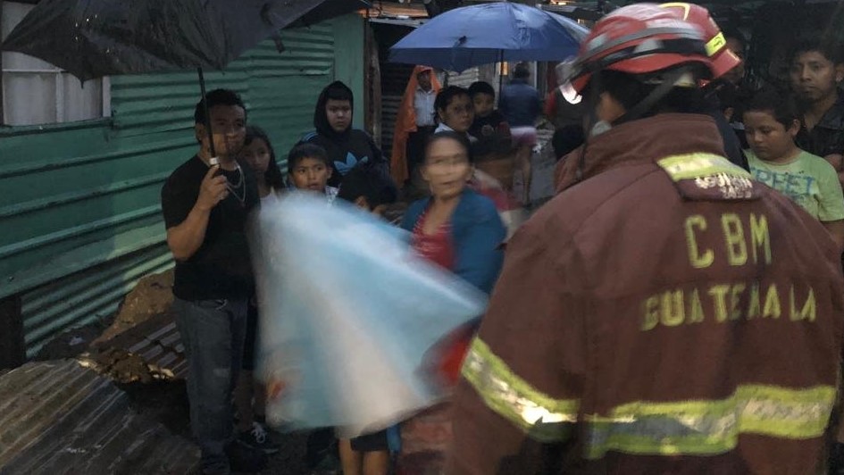 Un socorrista de Bomberos Municipales informa a los vecinos que la evacuación por riesgos a derrumbes en el asentamiento 5 de Octubre. (Foto Prensa Libre: Cortesía)