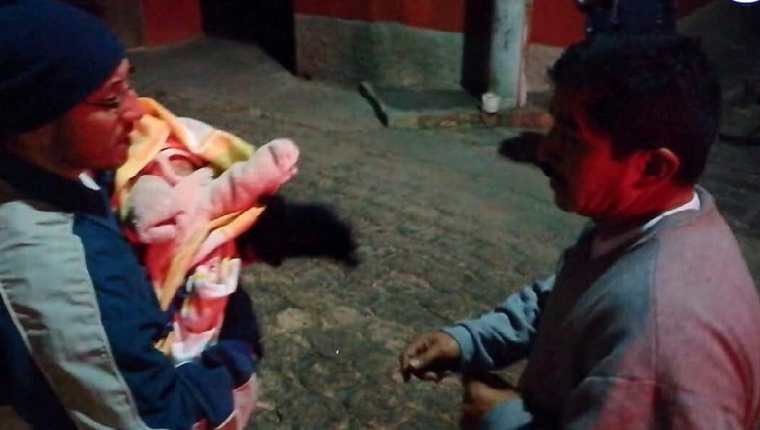 Vecino carga a bebé localizada en la ciudad de Quetzaltenango. (Foto Prensa Libre: Bomberos Voluntarios).
