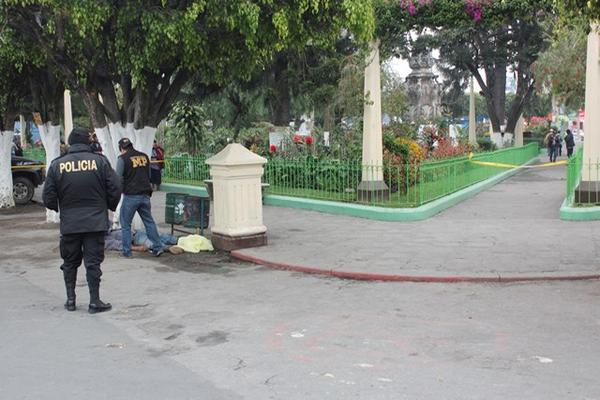 Agentes de la PNC y fiscales del Ministerio Público examinan cadáver de un hombre hallado en el parque central de Chimaltenango. (Foto Prensa Libre: Víctor Chamalé)