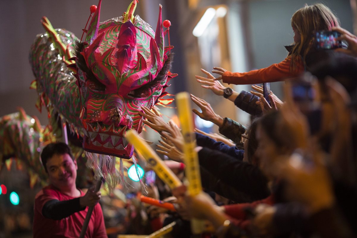 Público toca una figura de dragón hecha de papel en un desfile en Hong Kong. (EFE)
