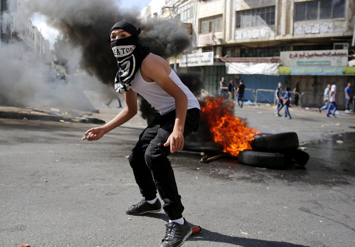 Manifestantes palestinos queman neumáticos durante enfrentamientos con soldados israelíes en la ciudad cisjordana de Hebrón.(Foto Prensa Libre: EFE).