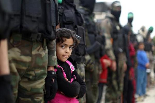 Una niña palestina junto a militantes de las brigadas de Ezzedine  al-Qassam, brazo armado del movimiento Hamás. (Foto Prensa Libre: AFP