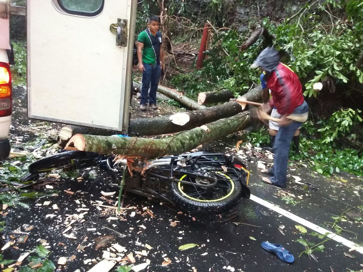 Vecinos cortan ramas de un árbol para rescatar a agente Jelman Samuel Baten Santay. (Foto Prensa Libre: PNC)