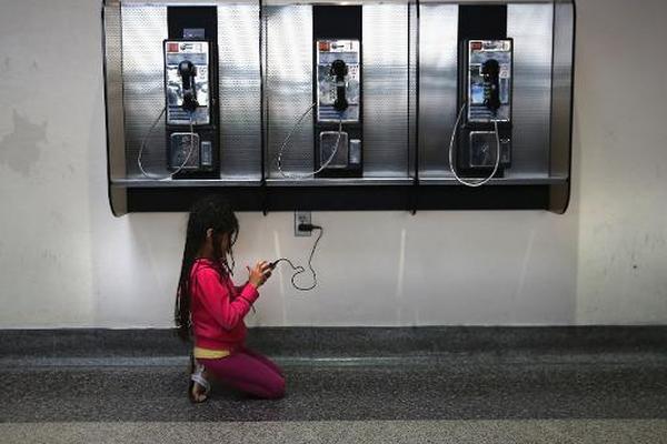 Una niña juega con un teléfono móvil en una estación de autobuses de Houston, EE. UU. (Foto Prensa Libre: AFP)