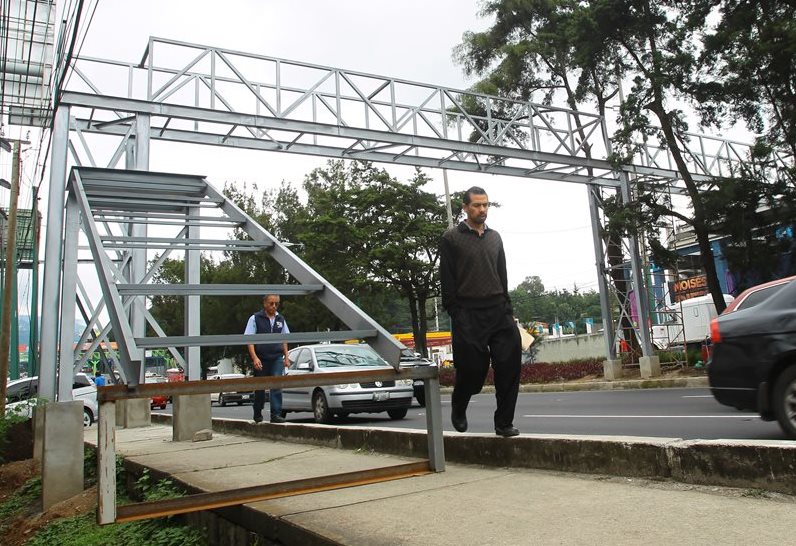 Vecinos que transitan por el kilómetro 14.5, calzada Roosevelt, son afectados por la construcción de pasarela que cubre la banqueta. (Foto Prensa Libre: Álvaro Interiano)