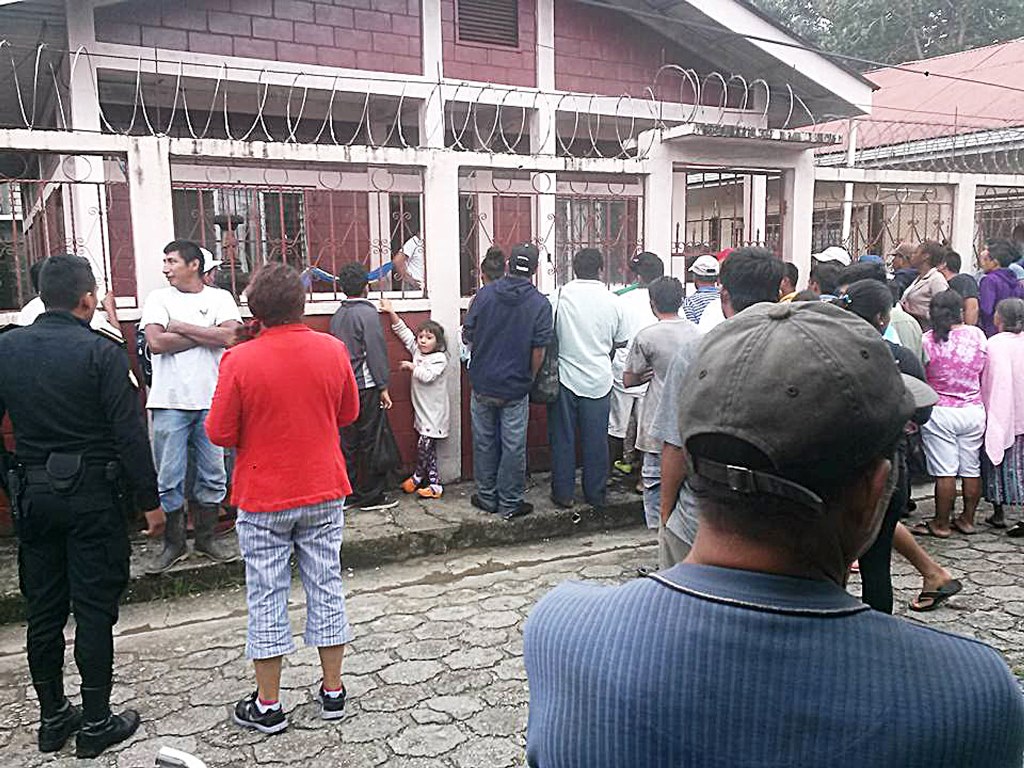 Pobladores de Lívingston, Izabal, observan el interior de vivienda donde se halla cadáver de septuagenario ultimado por su hijo. (Foto Prensa Libre: Dony Stewart)