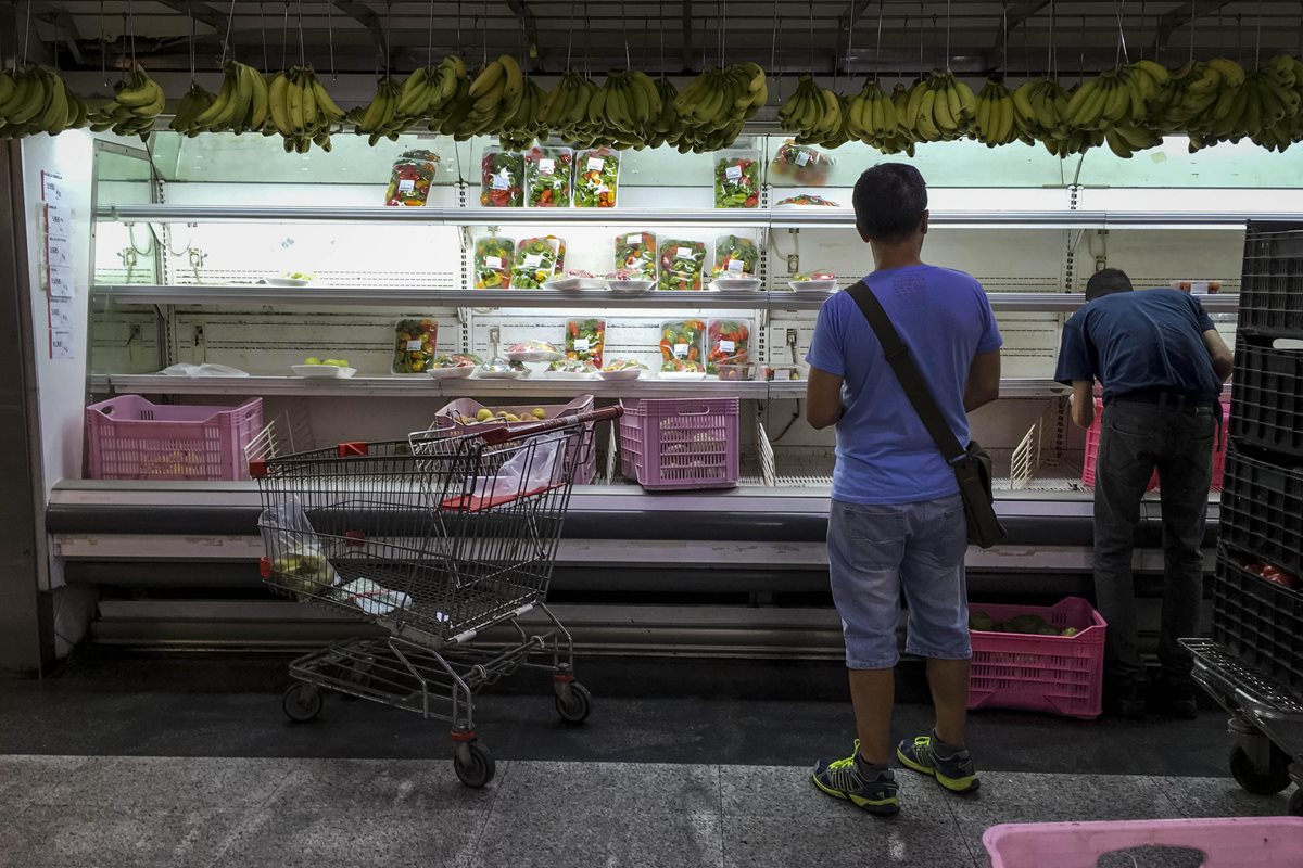 Venezolanos buscan alimentos en un supermercado con estanterías parcialmente vacías, en Caracas, Venezuela.(Foto Prensa Libre:EFE).