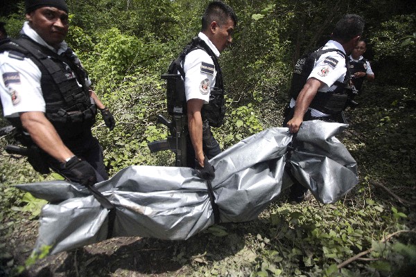 Agentes traladan a uno de los tres cadáveres encontrados en una fosa. (Foto Prensa Libre:AFP).