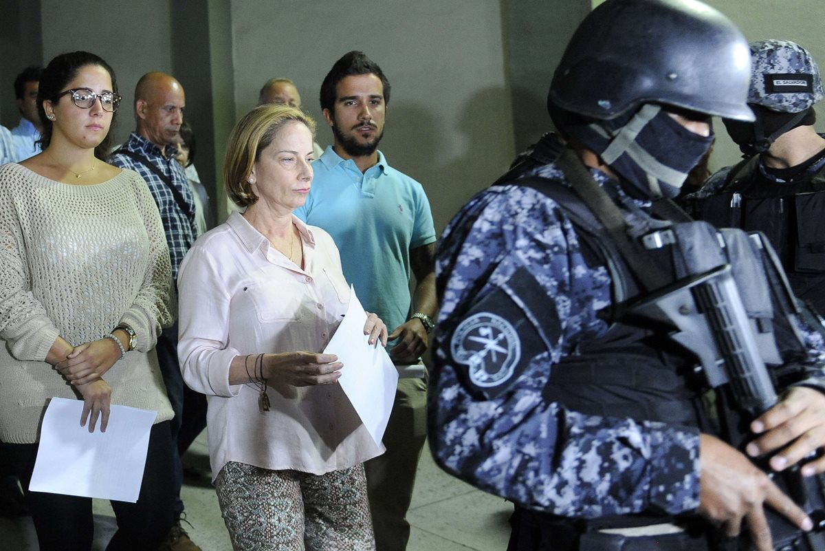 La esposa (centro) e hijos del fallecido expresidente Flores salen del hospital donde estuvo internado. (Foto Prensa Libre: AFP).