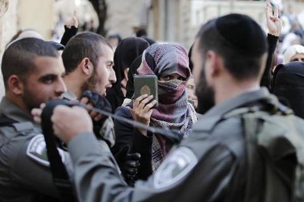 Una palestina muestra un ejemplar del Corán ante miembros de las fuerzas  de seguridad israelíes que le impedían el acceso a la Explanada de las  Mezquitas. (Foto Prensa Libre: AFP)