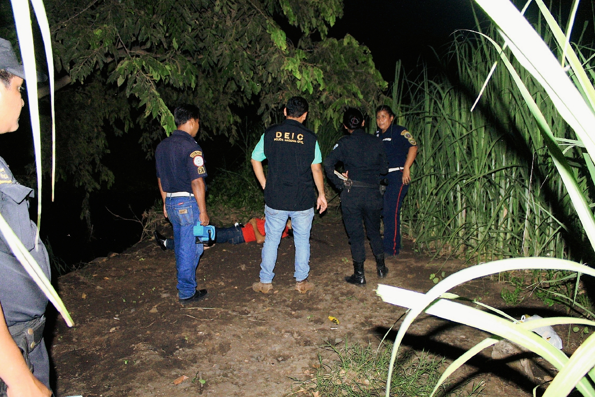 Agentes de  la PNC acordonan el área donde fue hallado el cadáver de un hombre en Masagua, Escuintla. (Foto Prensa Libre: Carlos E. Paredes)