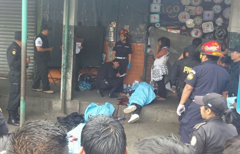 Locatarios observan los cadáveres, mientras socorristas los cubren. (Foto Prensa Libre: Cortesía)
