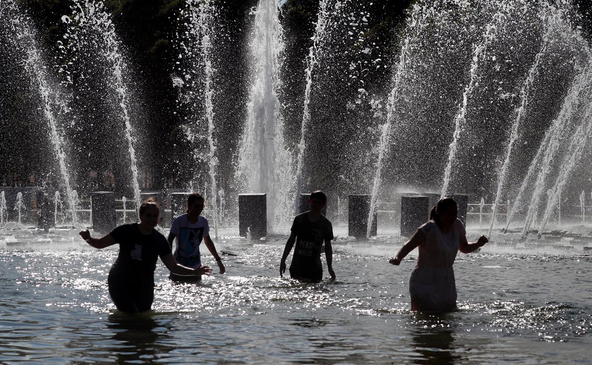 Varias personas se refrescan en una fuente del parque Gorki, en Moscú, Rusia. (Foto Prensa Libre:EFE)