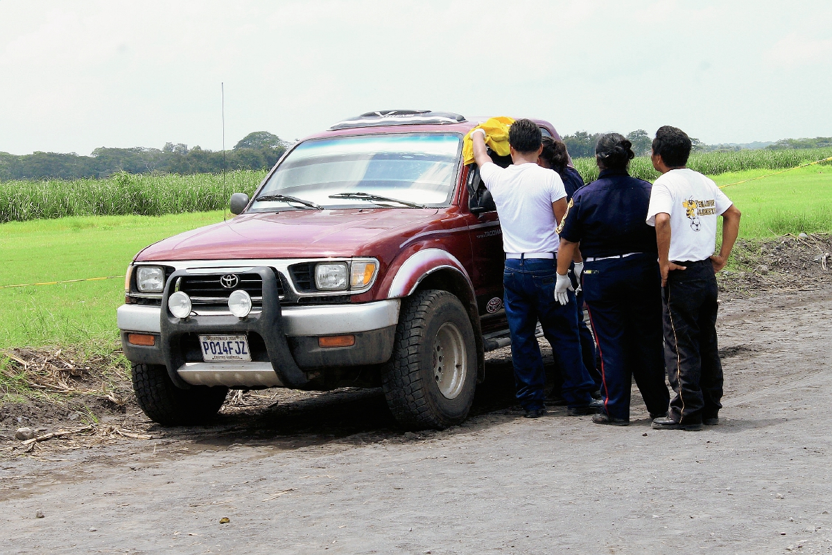 Socorristas examinan el cuerpo de Edin Morales, quien fue atacado a balazos en Masagua, Escuintla y murió. (Foto Prensa Libre: Carlos E. Paredes)