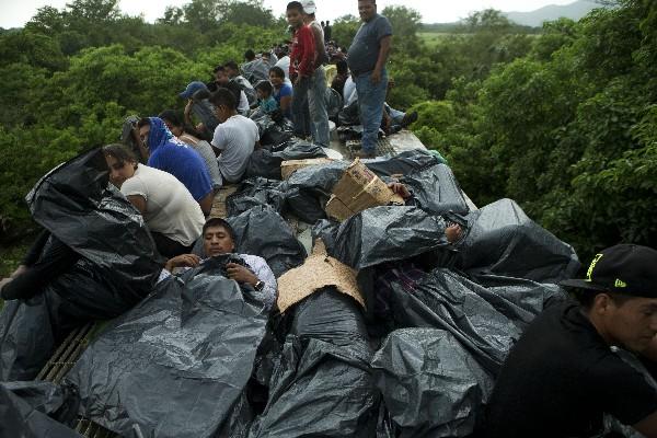 Migrantes viajan  en el techo del tren  la Bestia, mientras  tratan de protegerse de la lluvia.