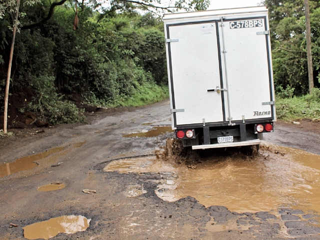 Un camión transita con dificultad por los grandes baches, en San Gabriel, San Antonio Palopó. (Foto Prensa Libre: Ángel Julajuj)