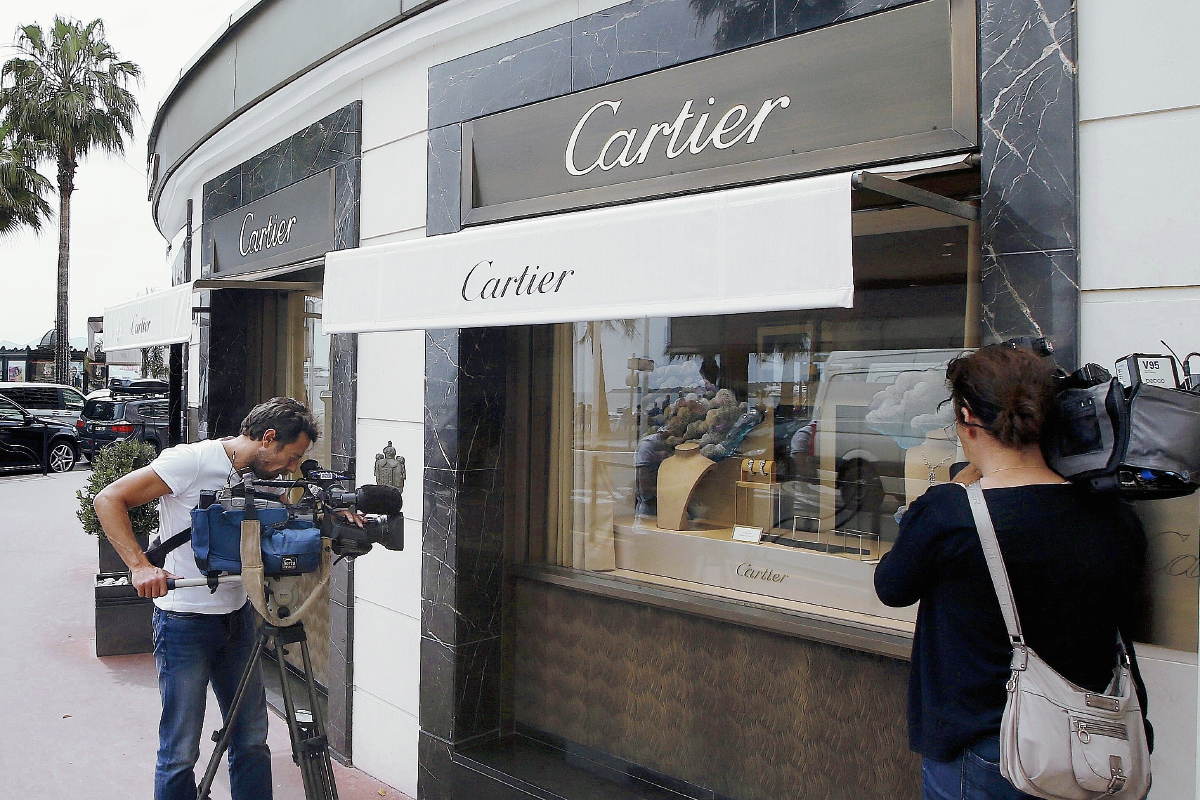 Periodistas trabajan en frente de la tienda de joyas de Cartier en la Croisette en Cannes, Costa Azul, donde se cometió el atraco. (Foto Prensa Libre: AFP).