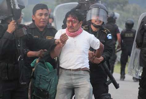 Pnc captura a uno de los campesinos. Inserto, dos  camiones arden en llamas.