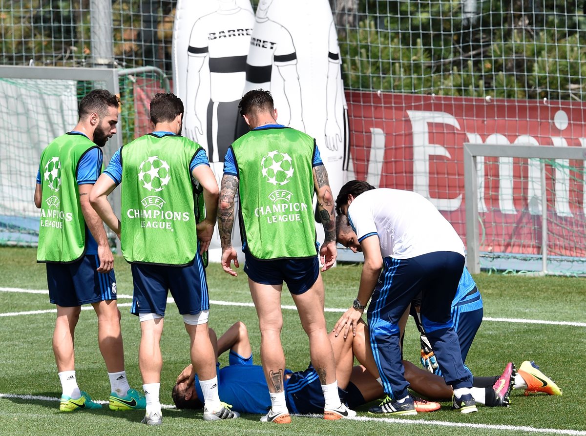 Cristiano Ronaldo se toma la cara y se queda del dolor mientras es atendido por los médicos del Real Madrid en el entrenamiento. (Foto Prensa Libre: AFP)