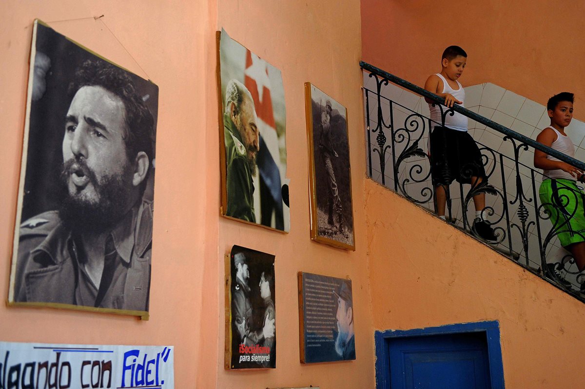 Estudiantes cubanos de primaria caminan por las escaleras, junto a una pared decorada con fotos de Fidel Castro. (AFP).