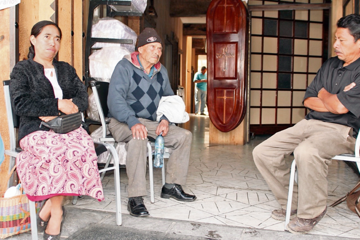 Élfego González, padre de mujer linchada —centro—, espera en una funeraria de San Marcos que le entreguen el cuerpo de su hija. (Foto Prensa Libre: Aroldo Marroquín)
