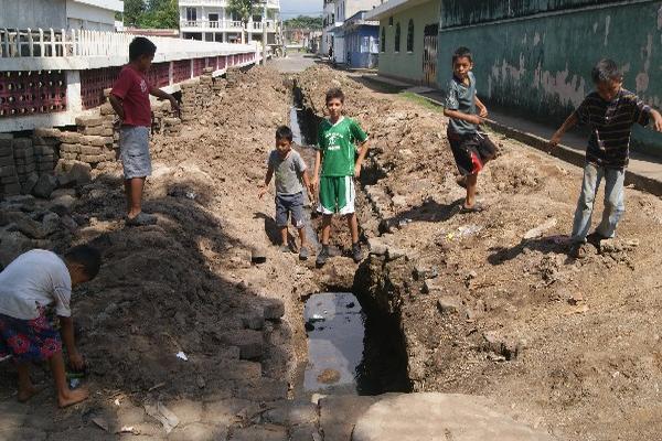 Niños juegan en una zanja abierta    en una calle de  la zona 4, de Retalhuleu.