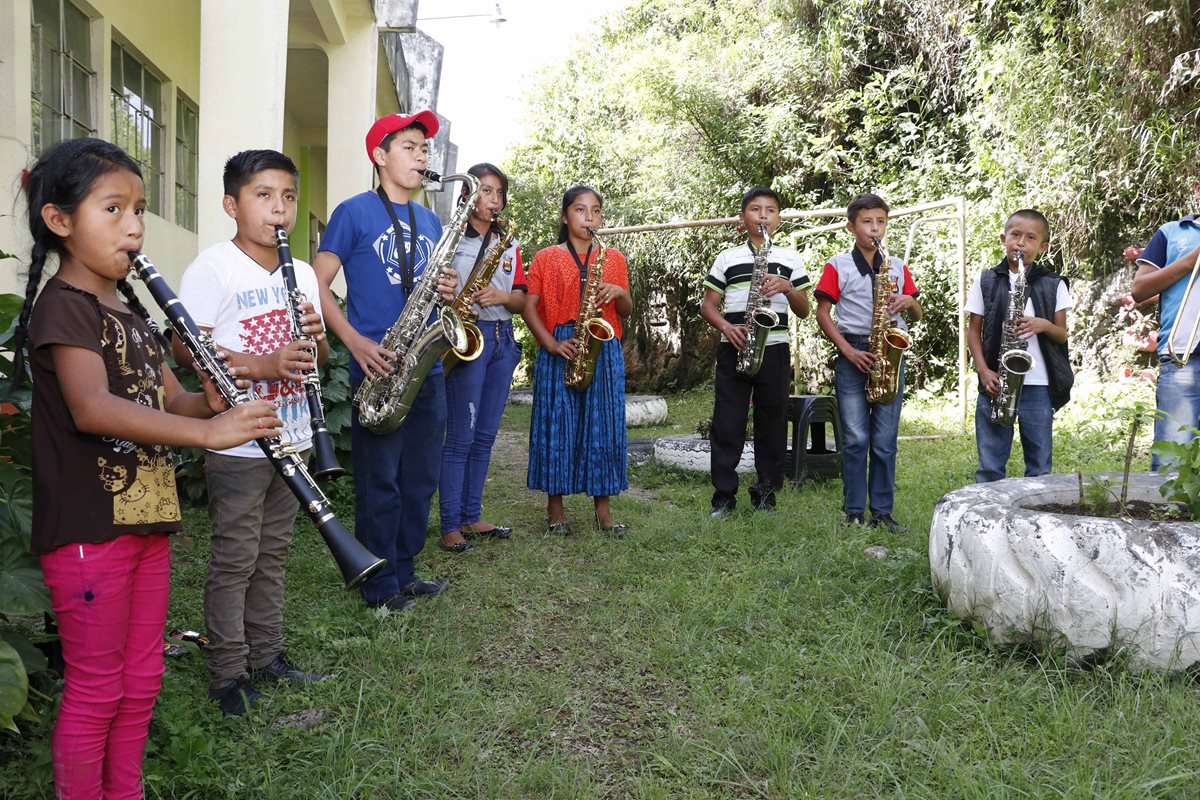 Jóvenes que aprenden a ejecutar instrumentos de viento practican en un espacio abierto afuera del gimnasio municipal de San Pedro Carchá. (Foto Prensa Libre: Eduardo Sam).