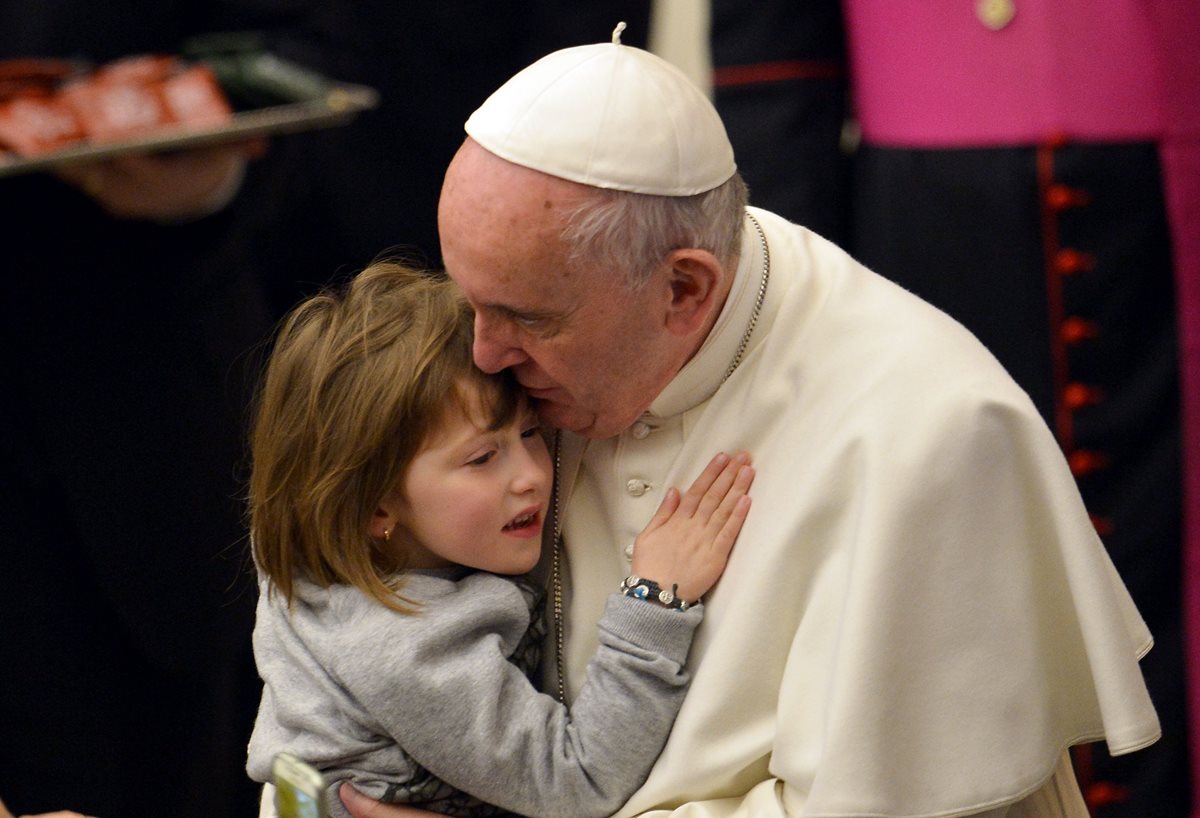 El papa Francisco abraza a una niña en el Vaticano. (Foto Prensa Libre: AFP).