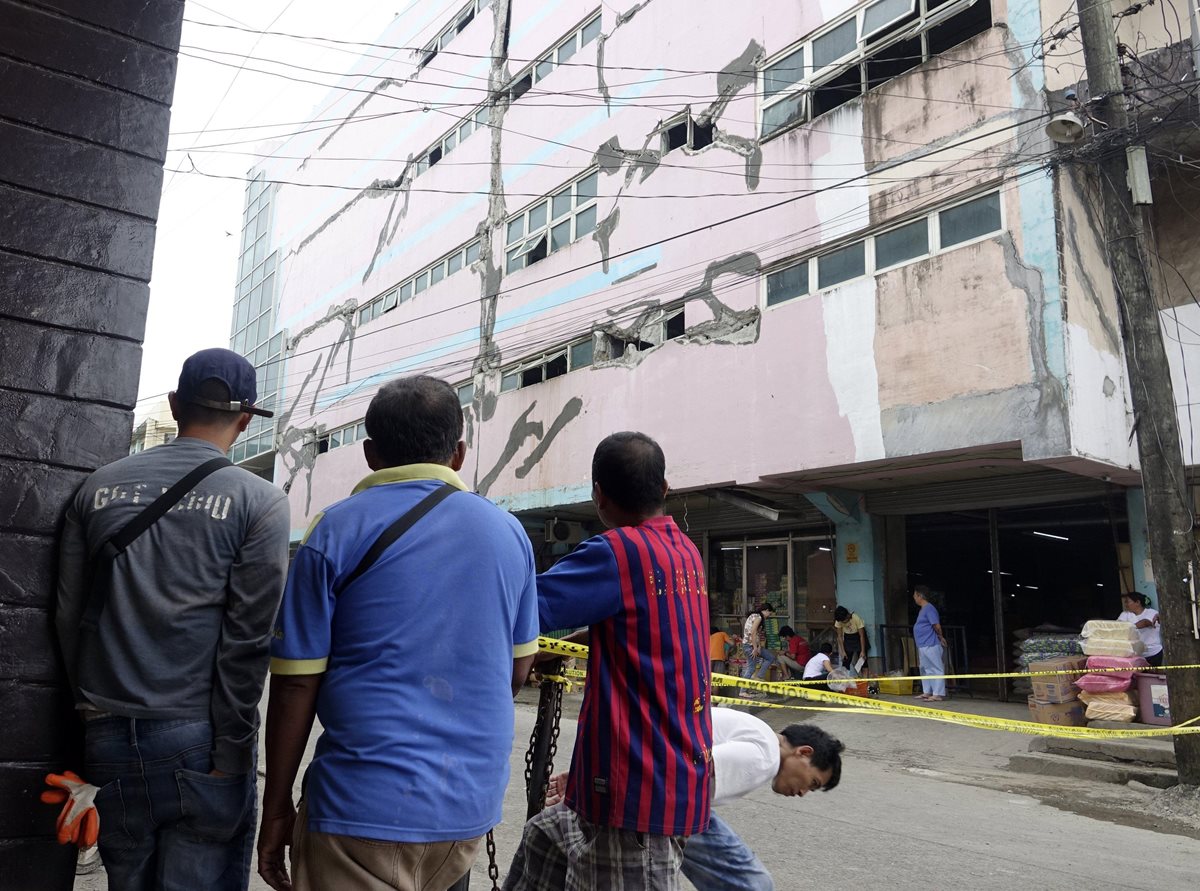 Habitantes de Surigao observan un edificio casi colapsado por el terremoto que sacudió Filipinas el sábado. (Foto Prensa Libre: EFE)